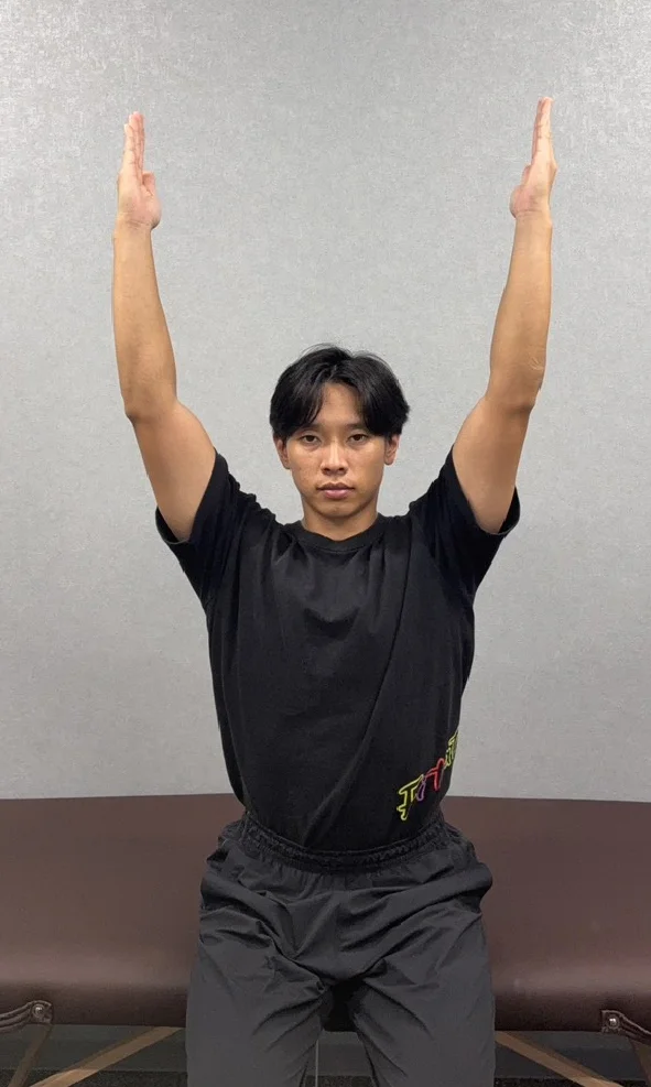 肩ストレッチ前の状態。腕が耳に付かない男性。