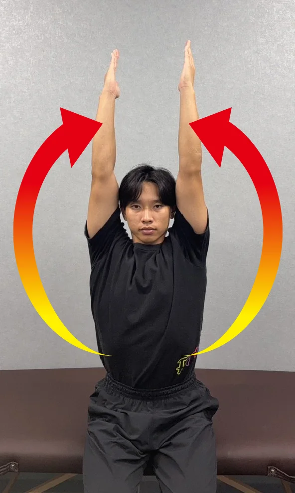 肩ストレッチ後の状態。腕が耳につく男性。