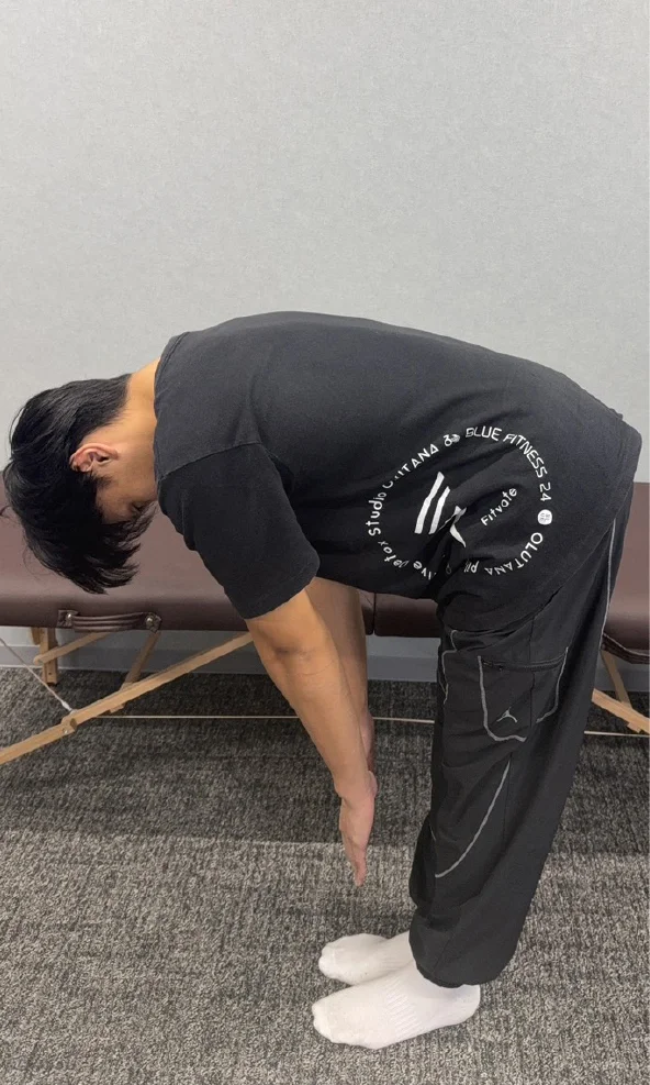 前屈で指が床に付かない男性。ストレッチ前の状態。